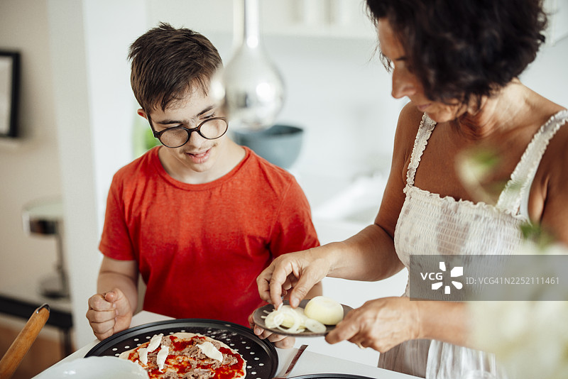 妈妈和儿子在家里的厨房一起做披萨图片素材