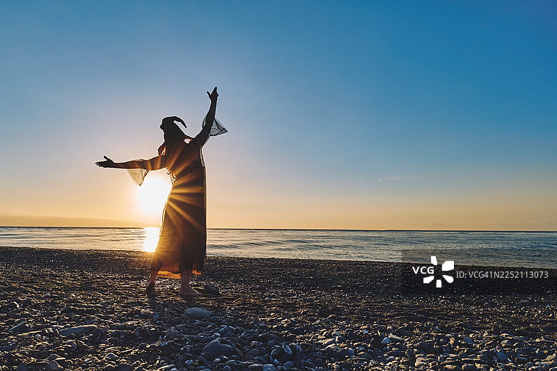 女巫身着戏服，在海边夕阳下摆姿势，为万圣节做准备图片素材