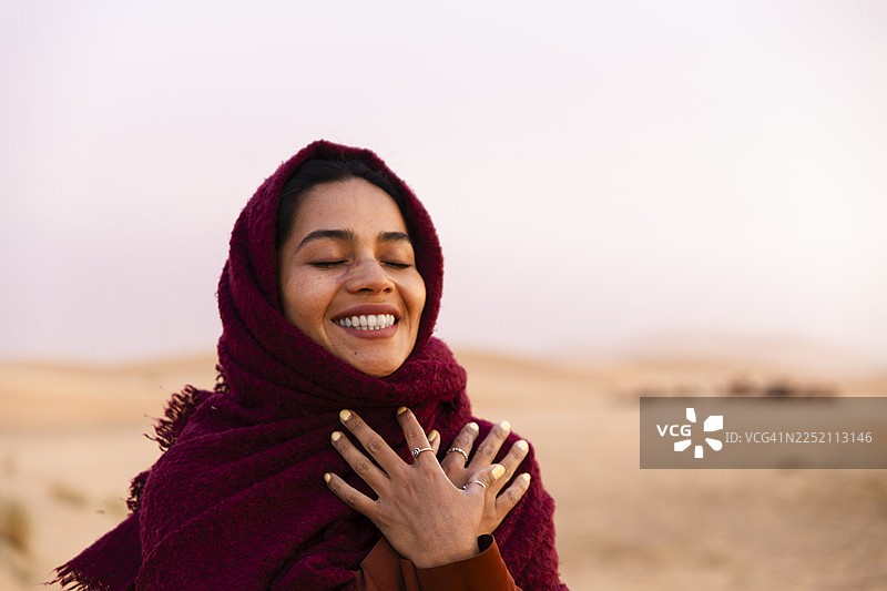 夕阳下撒哈拉沙漠中戴着头巾的肖像，展现出喜悦图片素材