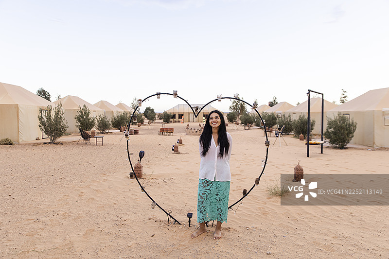 摩洛哥撒哈拉沙漠营地里，一个人站在心形画框中图片素材