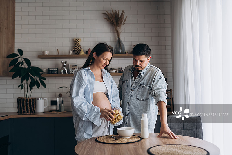 怀孕的妇女和伴侣在家一起准备早餐图片素材