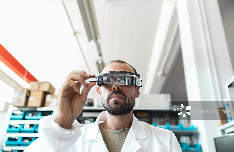 高科技电子车间里，实验室技术人员正在使用放大镜图片素材