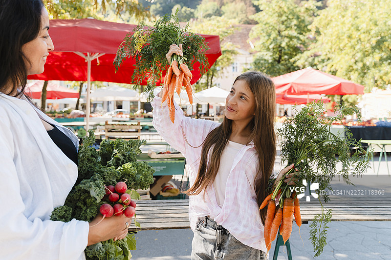 一位女士和她的女儿在当地市场挑选有机蔬菜图片素材