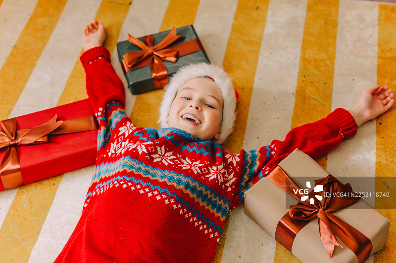 穿着毛衣的快乐孩子，脚下是地毯上的圣诞礼物图片素材