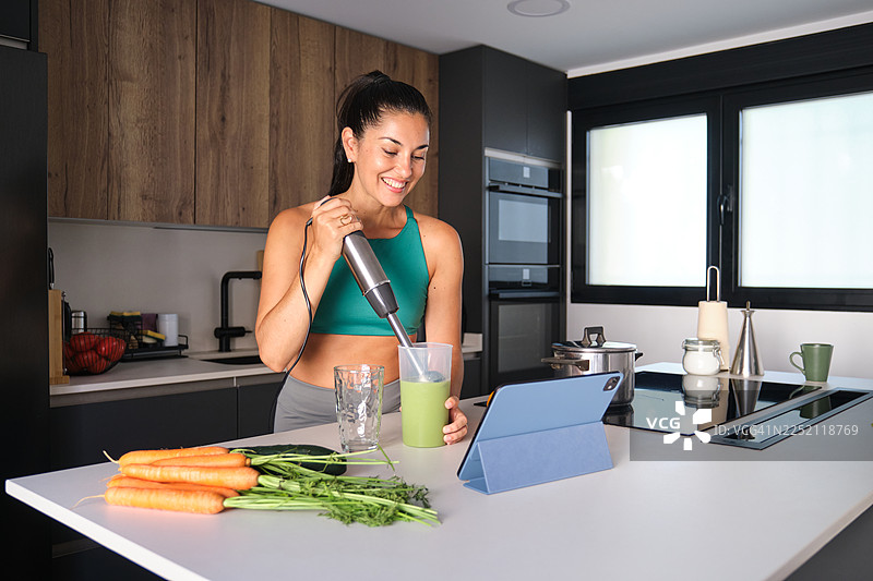 一位女性在现代厨房制作绿色冰沙，注重健身图片素材