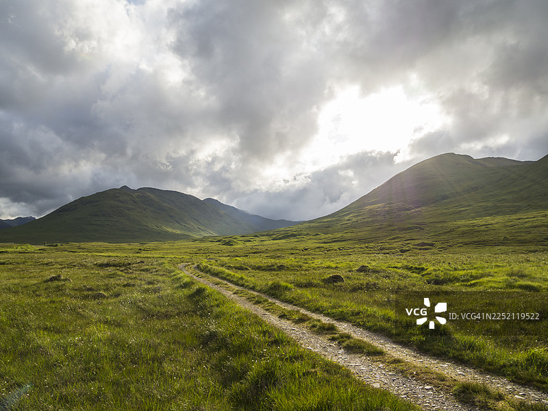 苏格兰格伦阿弗里克在阴云密布的天空下的路径，背景是山景。图片素材