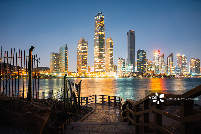 日落时分，中国山东青岛第三海水浴场上方的城市天际线闪耀着璀璨的光芒。图片素材