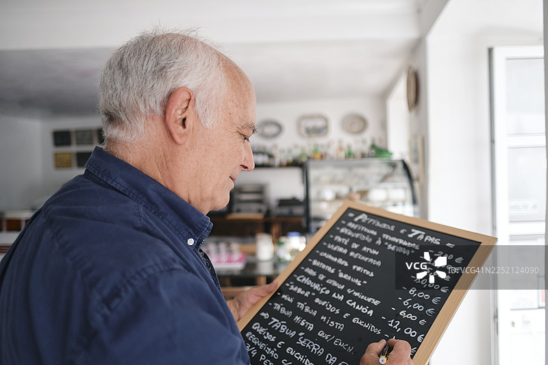 咖啡店老板在黑板上写菜单图片素材