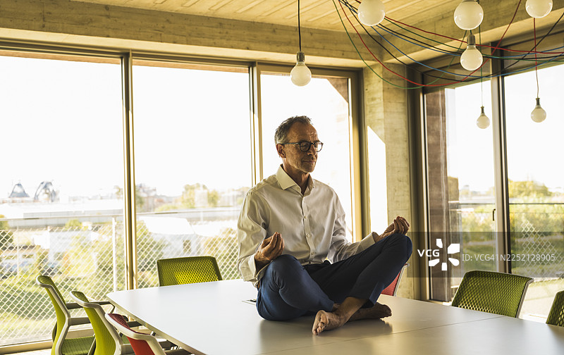 一位年长的商人正在会议桌上冥想图片素材