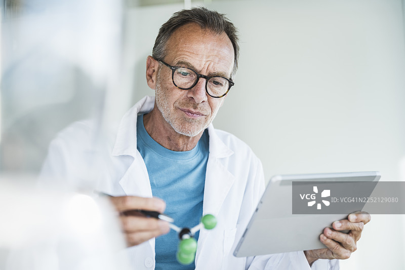 身穿实验服的老年男子正在研究分子结构图片素材