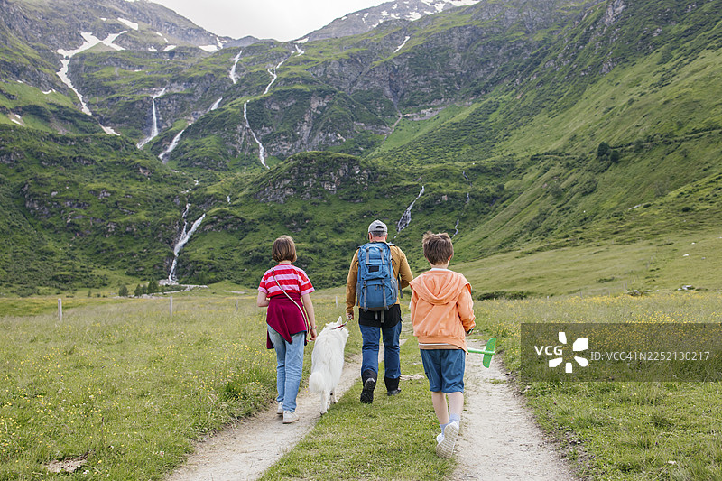 男人、孩子和狗在草地的小径上散步图片素材