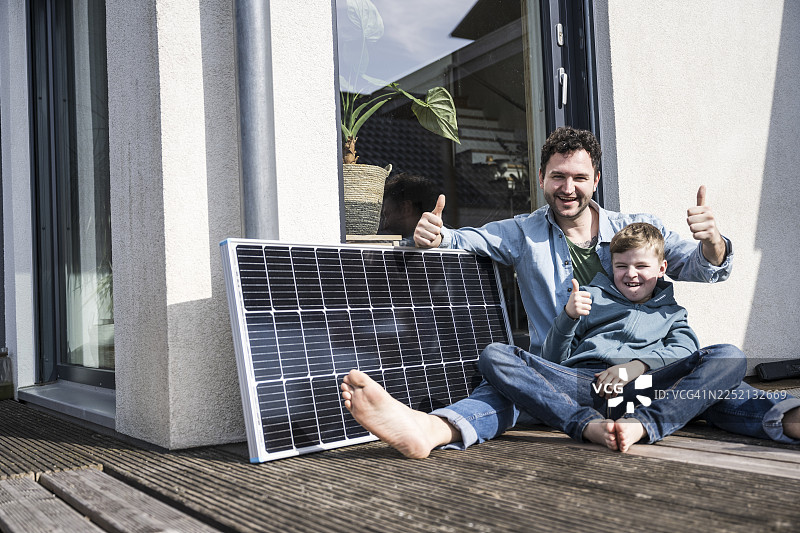父亲和儿子坐在装有太阳能电池板的露台上，享受着宝贵的亲子时光图片素材