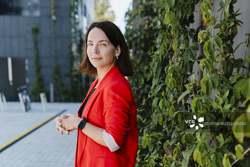 自信的专业人士身穿红色西装外套，在户外展现领导力和乐观精神图片素材