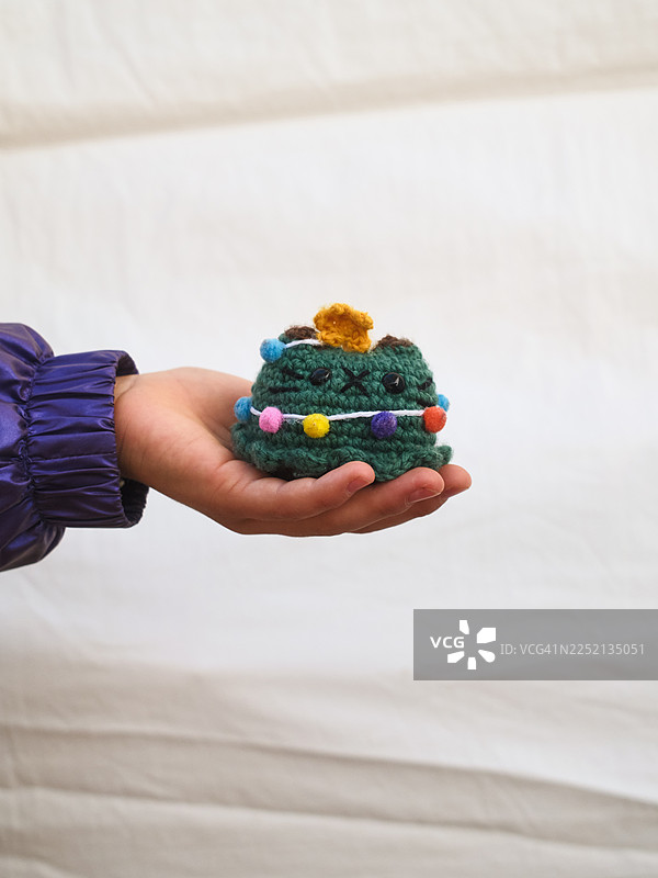 孩子手持手工钩针编织的圣诞树装饰品图片素材