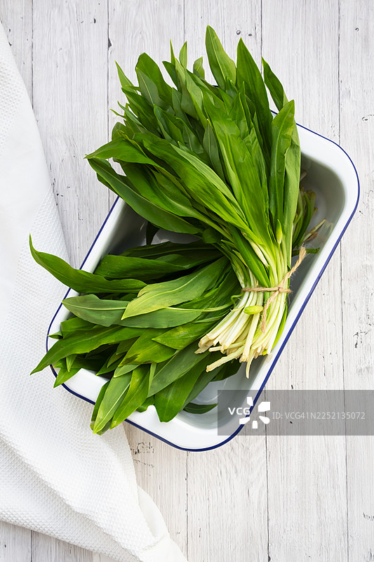 白色木质背景上的一束新鲜的野蒜图片素材