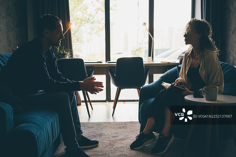 一位男士和一位女士在阳光明媚的现代办公室空间里进行深入交谈。图片素材
