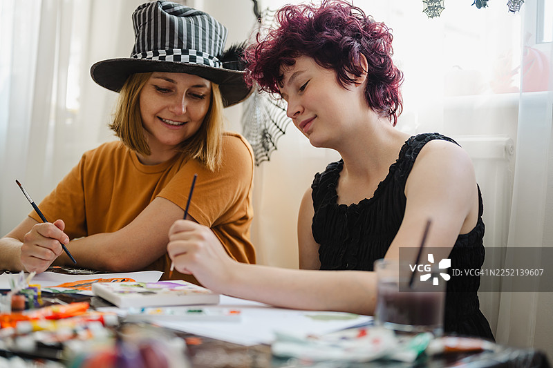 母亲和女儿在万圣节期间在家一起画画图片素材