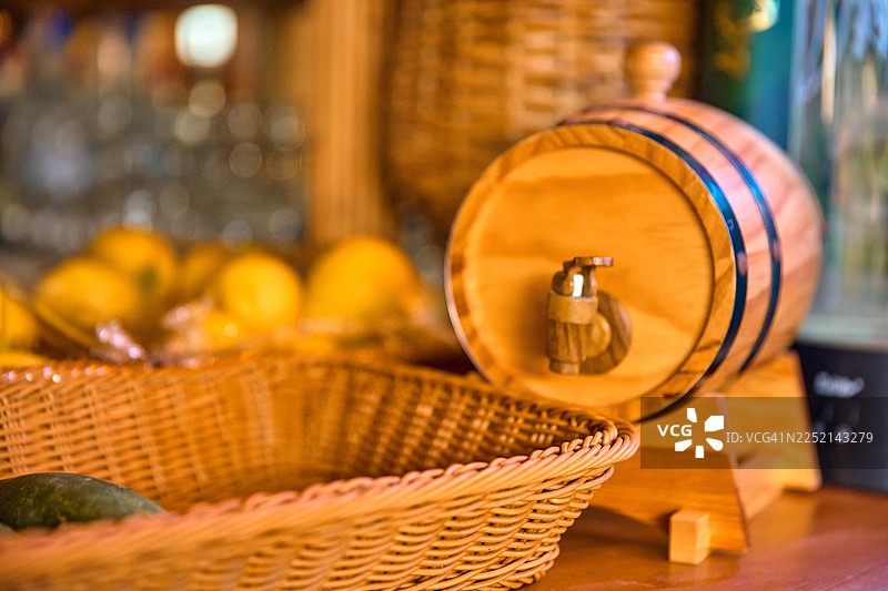 一个放在架子上的小型木桶旁边放着一个编织篮。图片素材