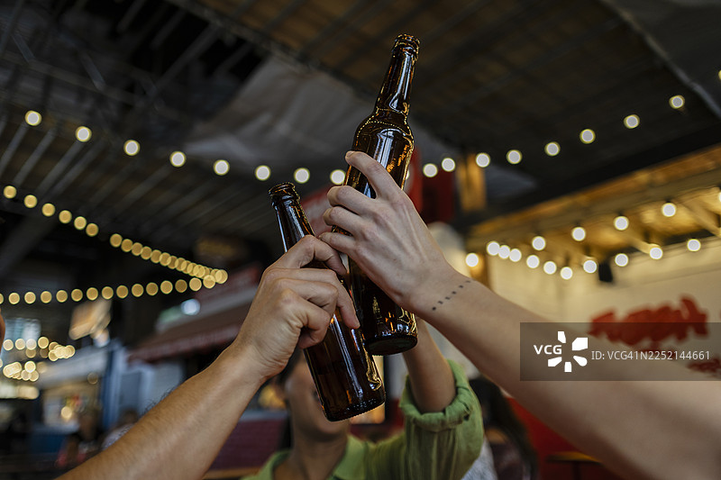 晚上在酿酒厂，朋友们用啤酒瓶庆祝图片素材