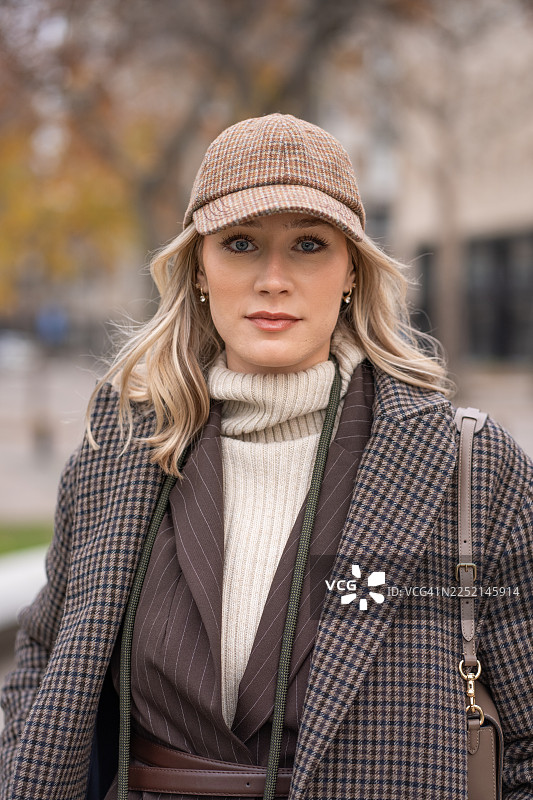 秋季风格肖像：一位身穿格子外套和帽子、置身于城市户外环境的女性图片素材