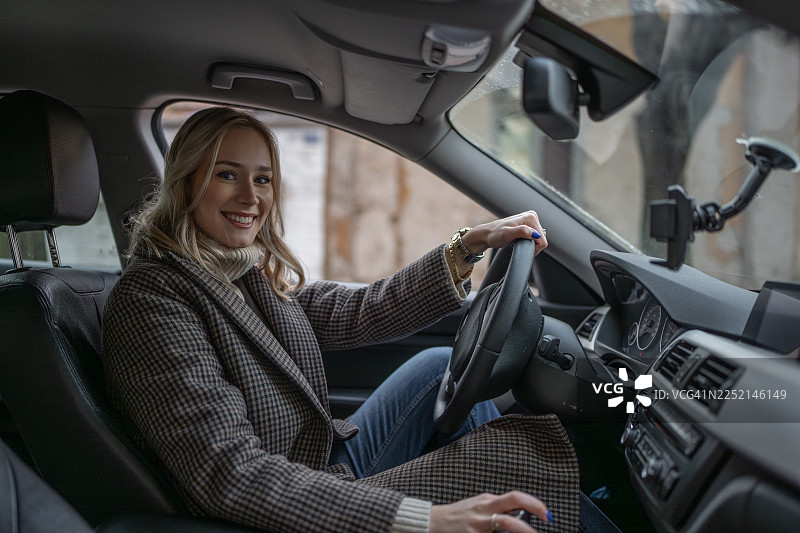 穿着舒适格子外套的微笑女性正在开车，准备好开启旅行与冒险图片素材