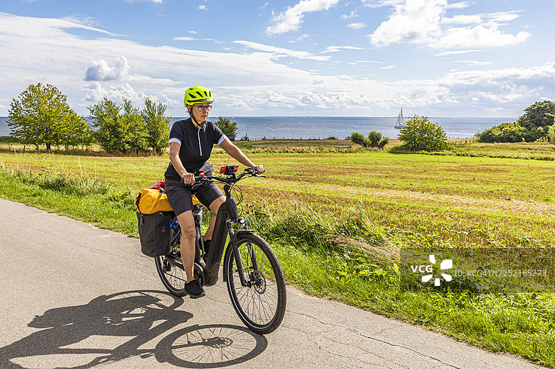 骑着电动自行车的骑行者沿着德国吕根岛的波罗的海自行车道骑行图片素材