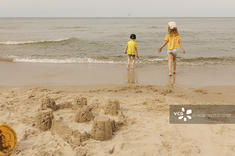 穿着黄色衣服的孩子们在海边沙滩上玩耍图片素材