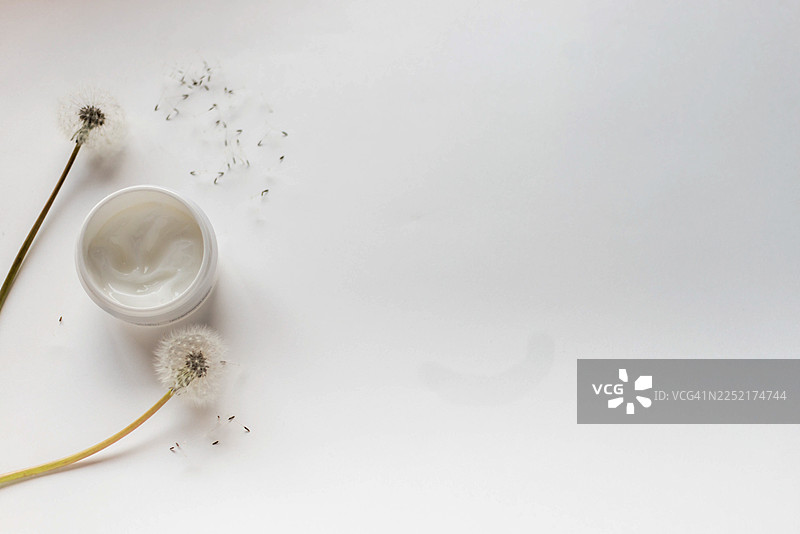白底上带有蒲公英草药的化妆品面霜罐图片素材