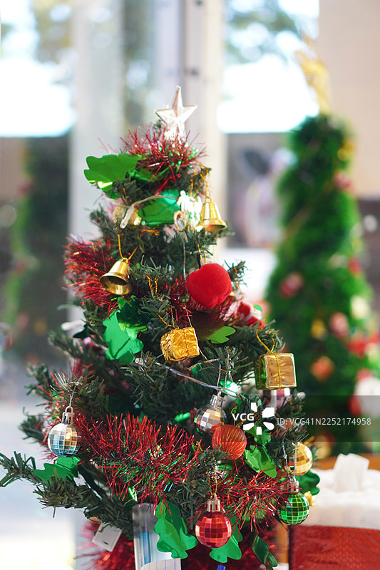 装饰精美的圣诞绿树，有金色礼盒和叶子，背景模糊。装饰好的圣诞树，背景模糊。图片素材