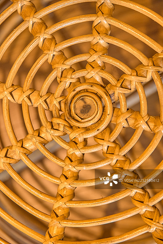 特写镜头，一个手工编织的藤椅座位，带有圆形图案。图片素材