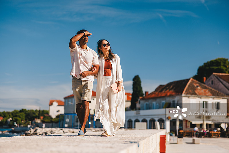 时尚情侣漫步在阳光明媚的达尔马提亚码头图片素材