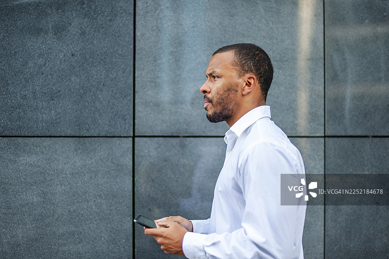 商务人士在户外使用手机行走的侧面视图图片素材