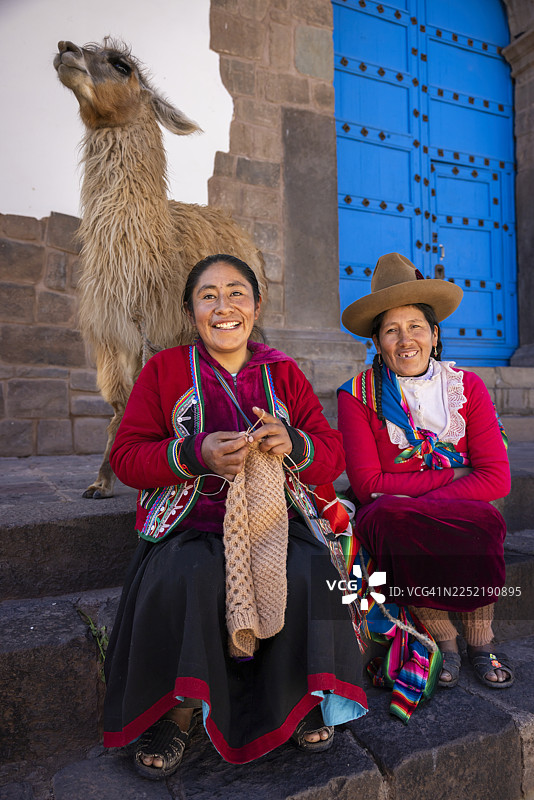 秘鲁妇女身着传统服饰，在库斯科与羊驼合影图片素材