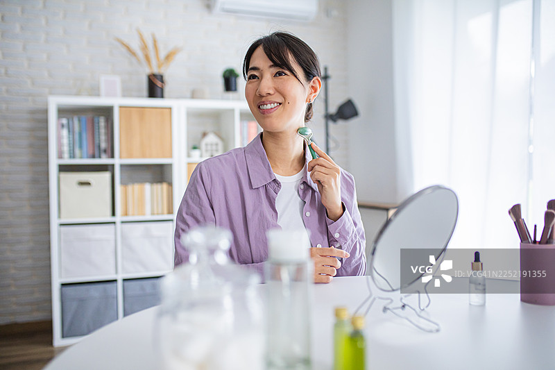 微笑的女性正在进行面部自我按摩图片素材