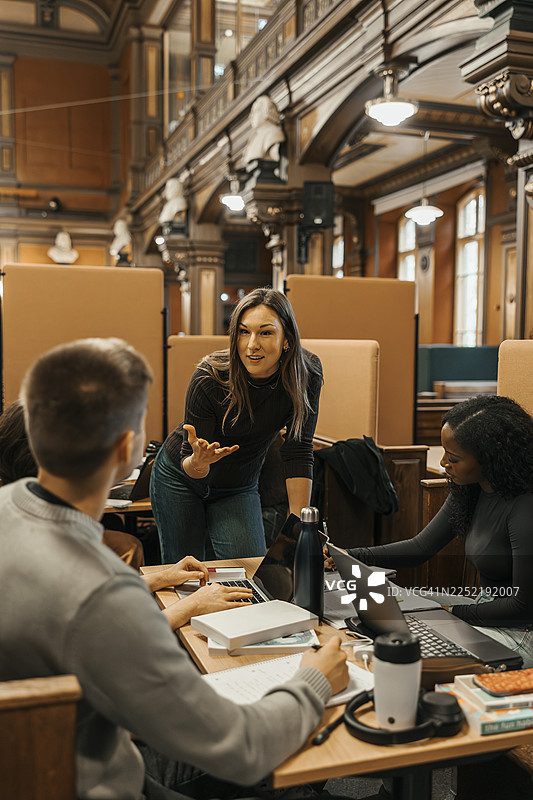 女大学生在大学图书馆与朋友分享想法，共同完成小组项目图片素材