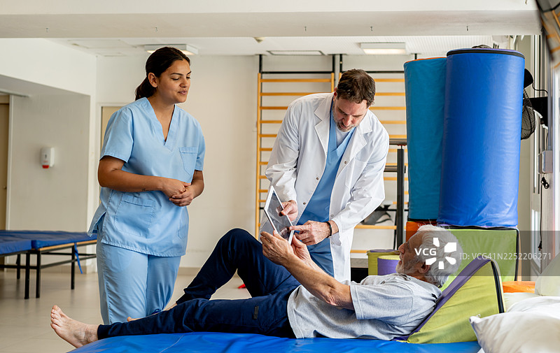 医生在进行物理治疗时，向一位老年患者展示一些X光片图片素材