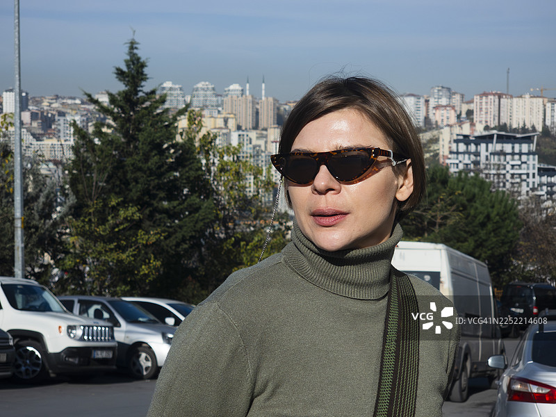 戴着太阳镜和高领衫的女子，背景是伊斯坦布尔城市景观图片素材