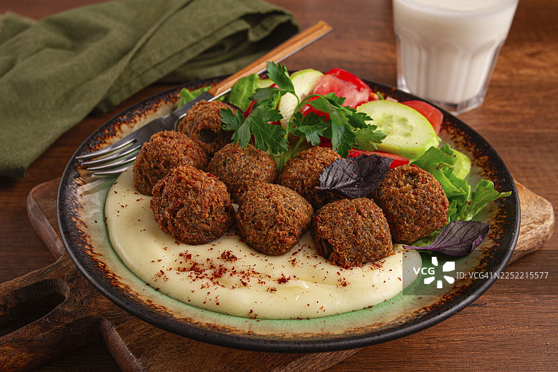 盘子里装着沙拉三明治、芝麻酱、番茄黄瓜沙拉和一杯饮品。温馨诱人的氛围，是享用新鲜食材午餐的完美选择。图片素材