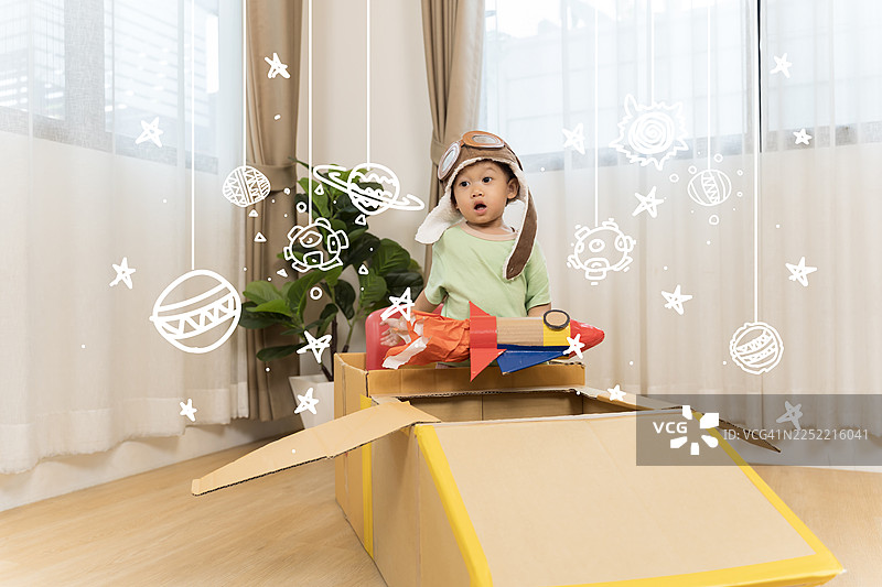 蹒跚学步的孩子在纸板火箭中扮演宇航员，充满想象力和创造力图片素材