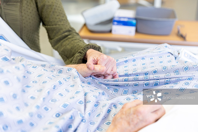 年迈的男人躺在病床上，妻子在一旁陪伴支持图片素材