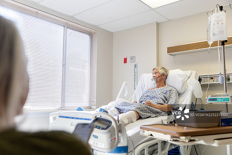 年长的男人躺在病床上，他的妻子在旁支持他图片素材