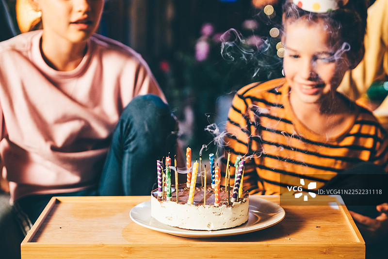 一个快乐的家庭，有两个孩子，在夜晚的户外庆祝生日，有蛋糕和仙女棒。图片素材