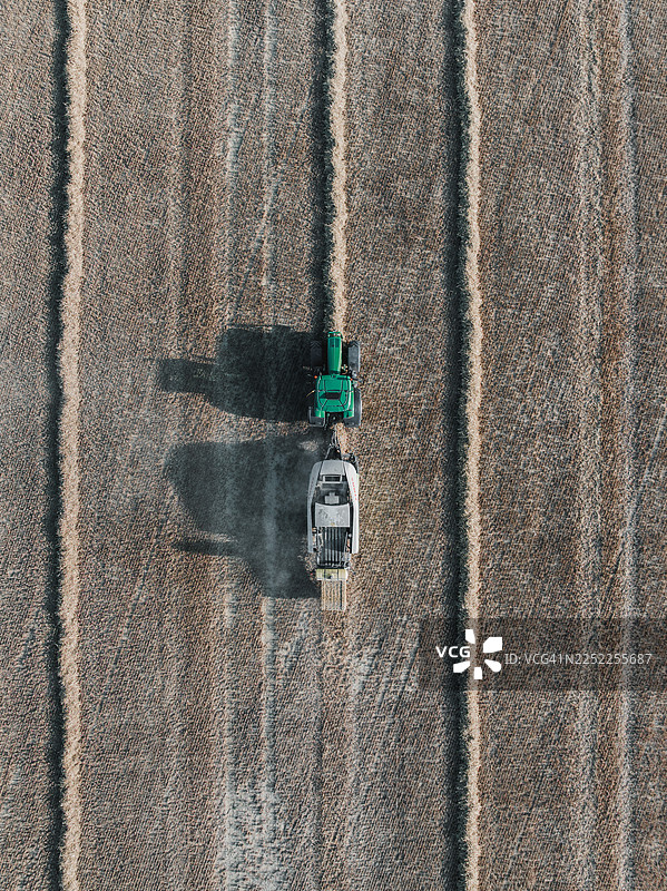 无人机视角，英国伍尔弗汉普顿田野里拖着打捆机的拖拉机图片素材