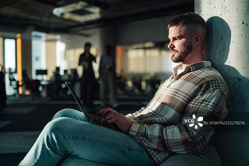 年轻人在现代办公室用笔记本电脑工作图片素材