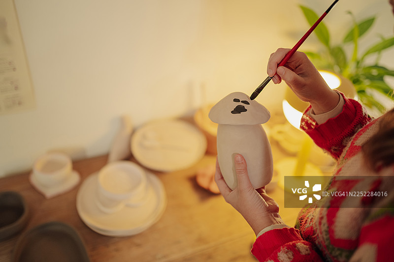 一个人在画可爱的陶瓷蘑菇，陶艺手工爱好图片素材