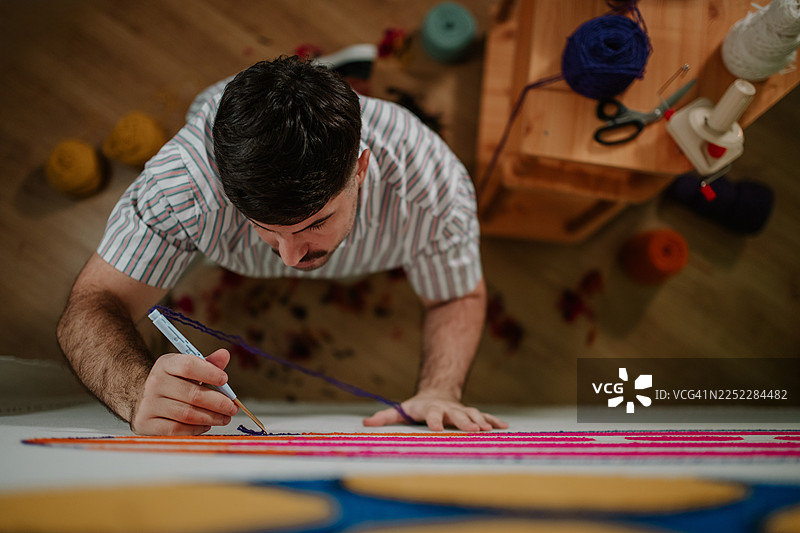 男人正在簇绒彩色地毯，制作手工工艺品图片素材