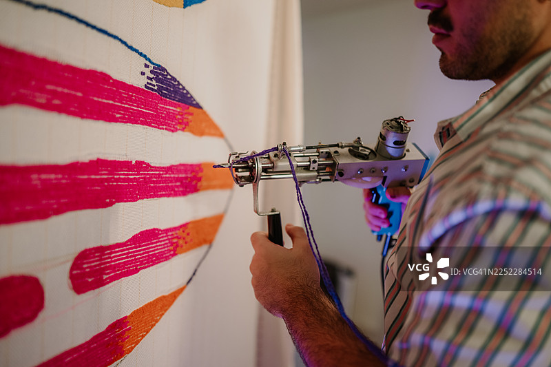 一个人用簇绒枪制作彩色地毯图片素材