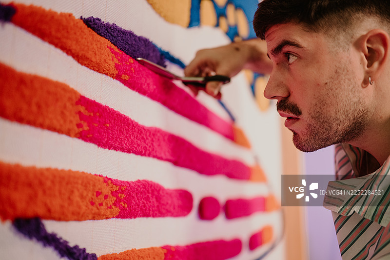男人制作色彩缤纷的簇绒纺织艺术品的创意过程图片素材