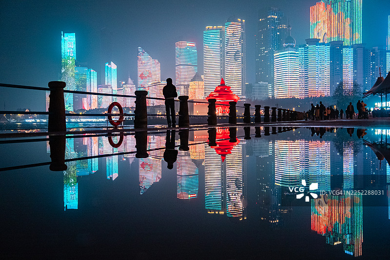 一位年轻貌美的女子在中国山东青岛第三海水浴场上空，城市天际线在她身后闪耀。图片素材