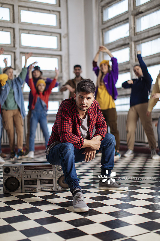 年轻男子在舞蹈室里拿着录音机摆姿势图片素材